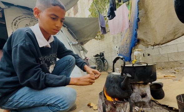 Mahmoud Sultan varmer opp vann og mat utenfor teltet sitt.