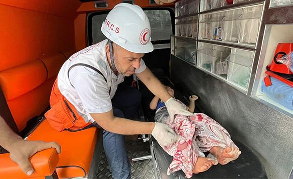 Helsearbeider fra Røde Halvmåne hjelper et skadet barn i en ambulanse