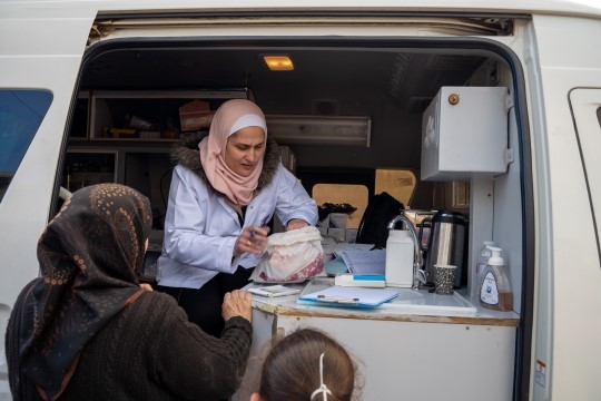 En kvinne tilbyr helsehjelp fra en bil. 