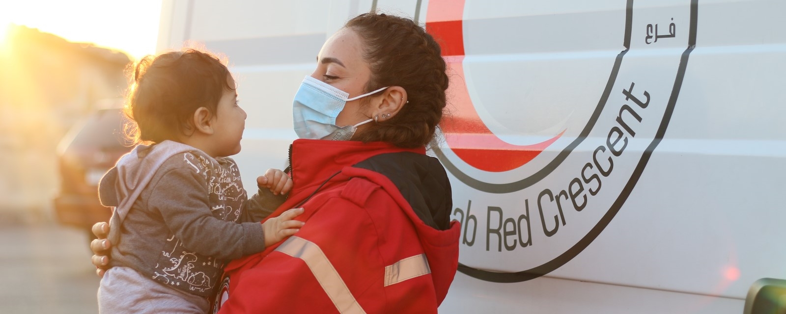 En kvinnelig hjelpearbeider holder et lite barn i armene.
