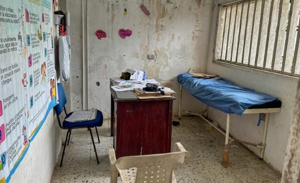 Et undersøkelsesrom for pasienter med en stol, skrivebord og en enkel benk.