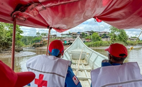 En båt med to personer kjører inn mot en liten landsby som ligger langs elva Chagüi i Colombia.