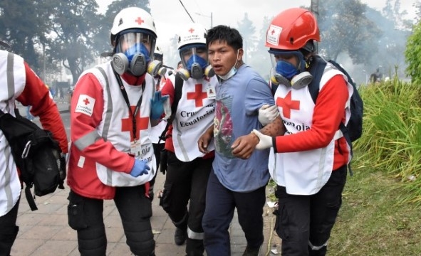 Tre frivillige fra Røde Kors hjelper en mann bort fra et område med opptøyer.