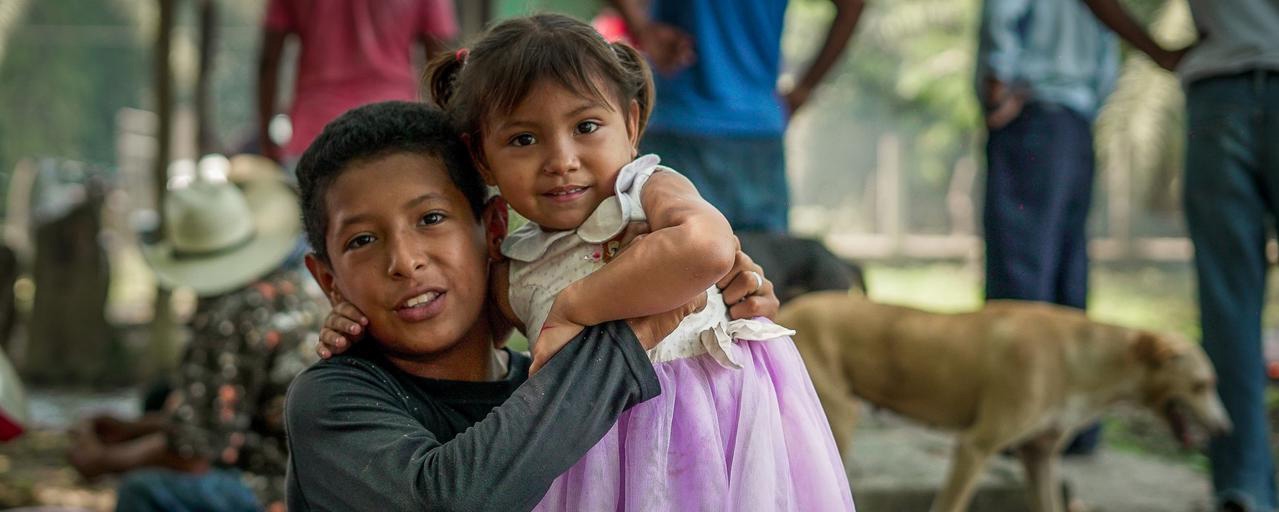 En liten gutt klemmer en liten jente.