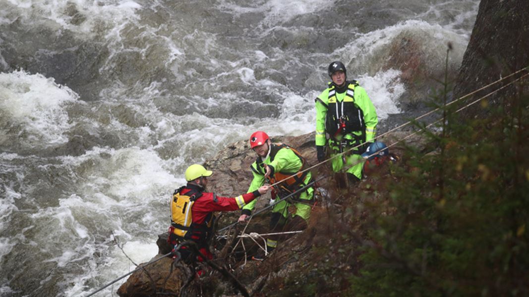 En gruppe hjelpekorps står rett ved et hissig stryk med budrende vann
