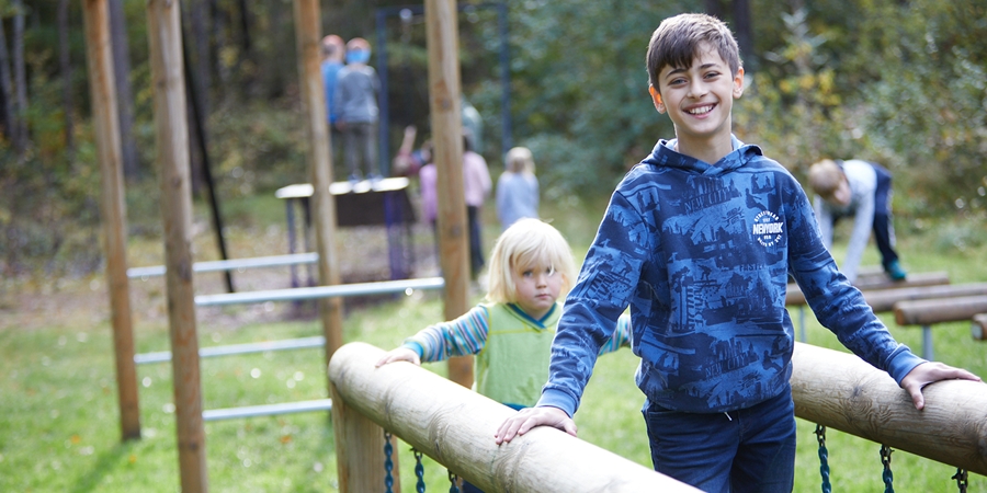 En gut og en liten jente på lekestativ ute, dag.