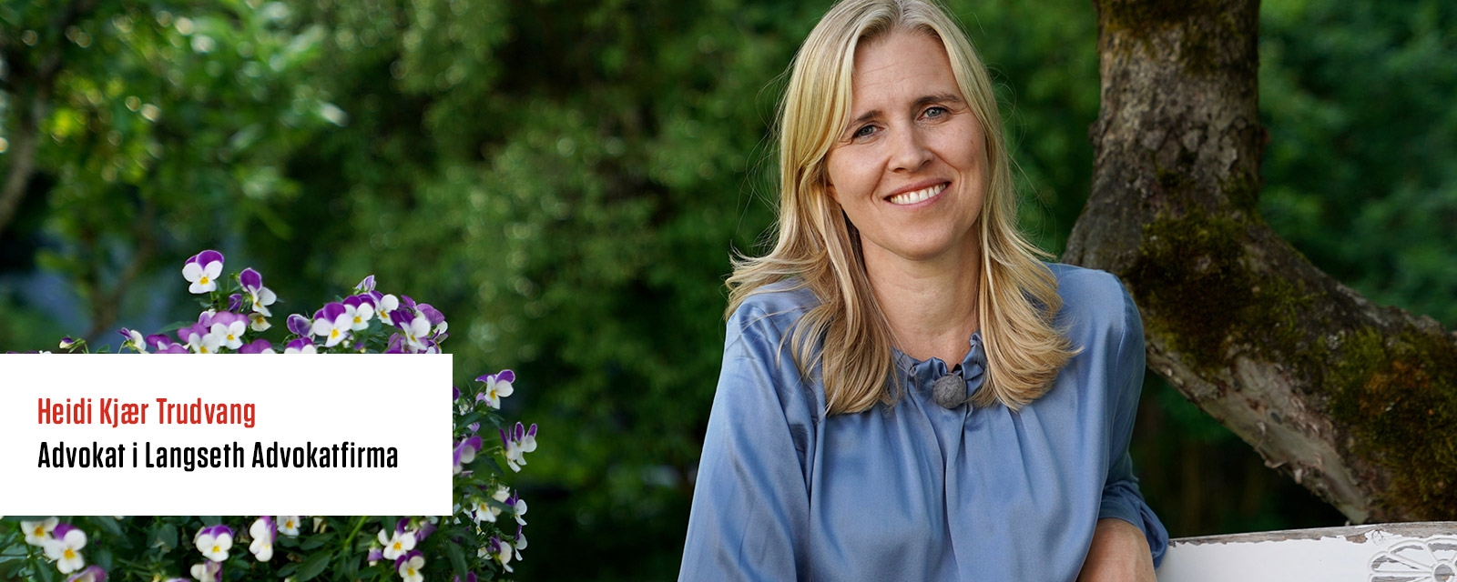 Smilende dame sitter i en hage