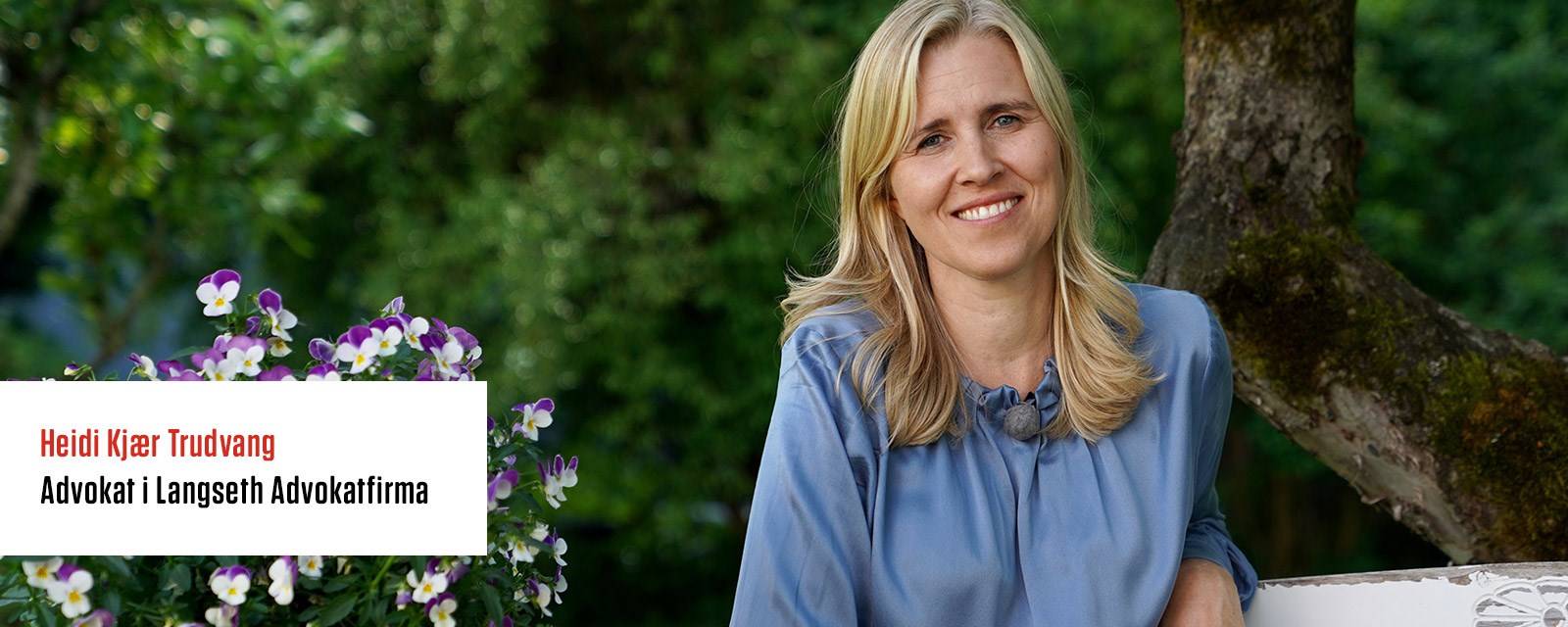 Smilende dame sitter i en hage