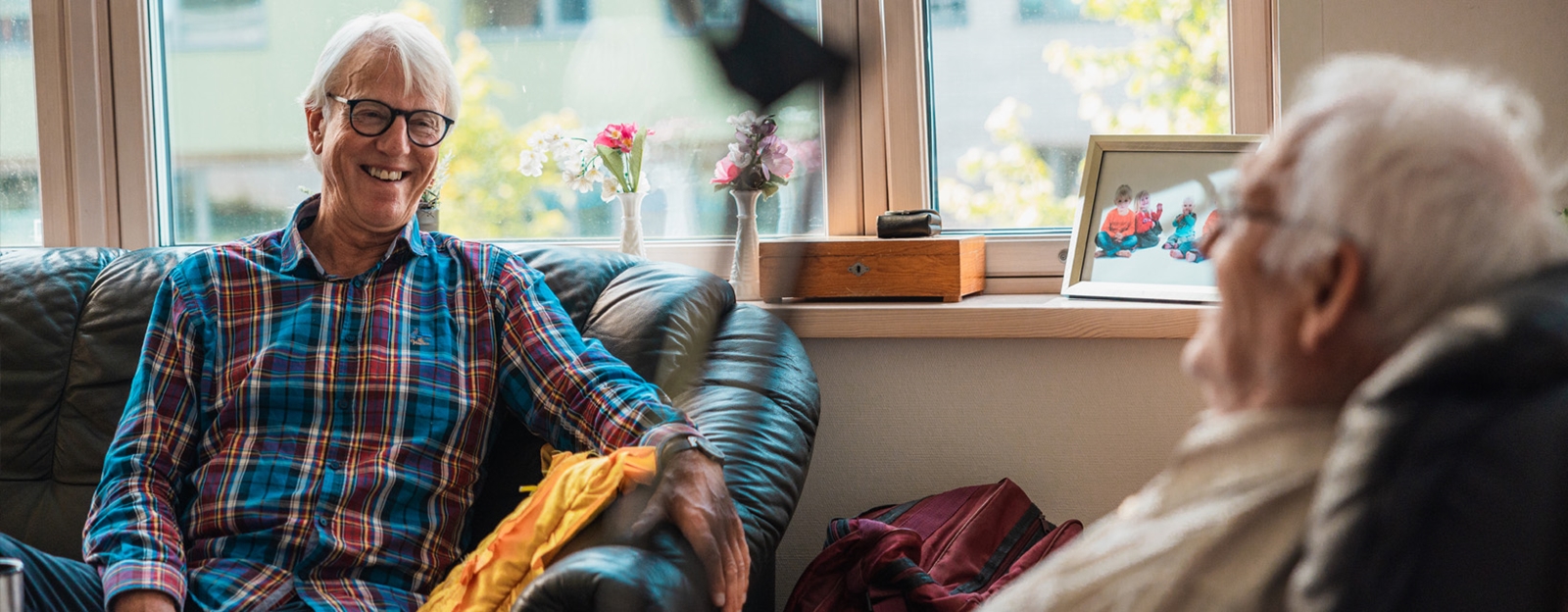 to eldre menn ler og ser på hverandre fra hver sin stol.