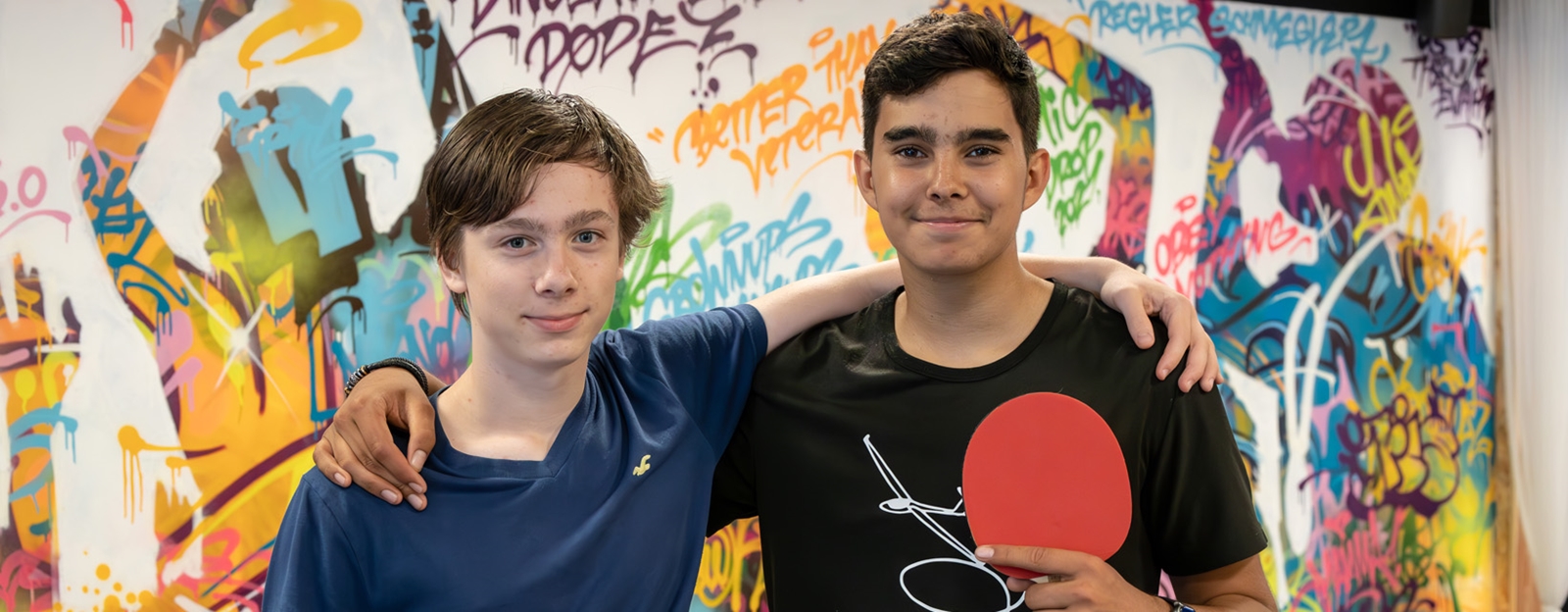 To ungdomsgutter står sammen og holder bordtennisracket