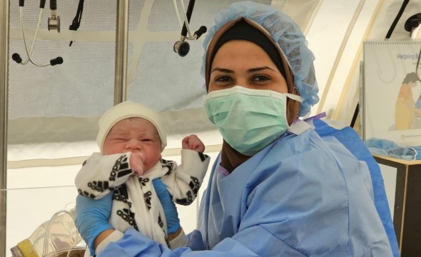 Nyfødt baby holdes i hendene til helsepersonell på feltsykehuset i Gaza