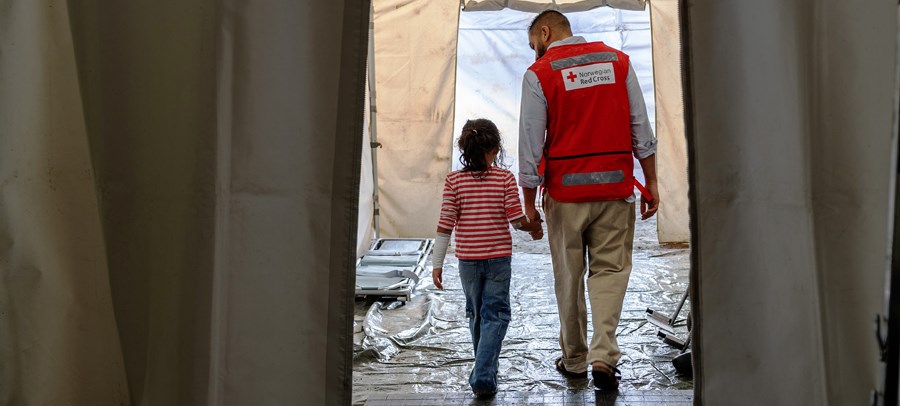 Barn holder hånda til en voksen fra Røde KOrs