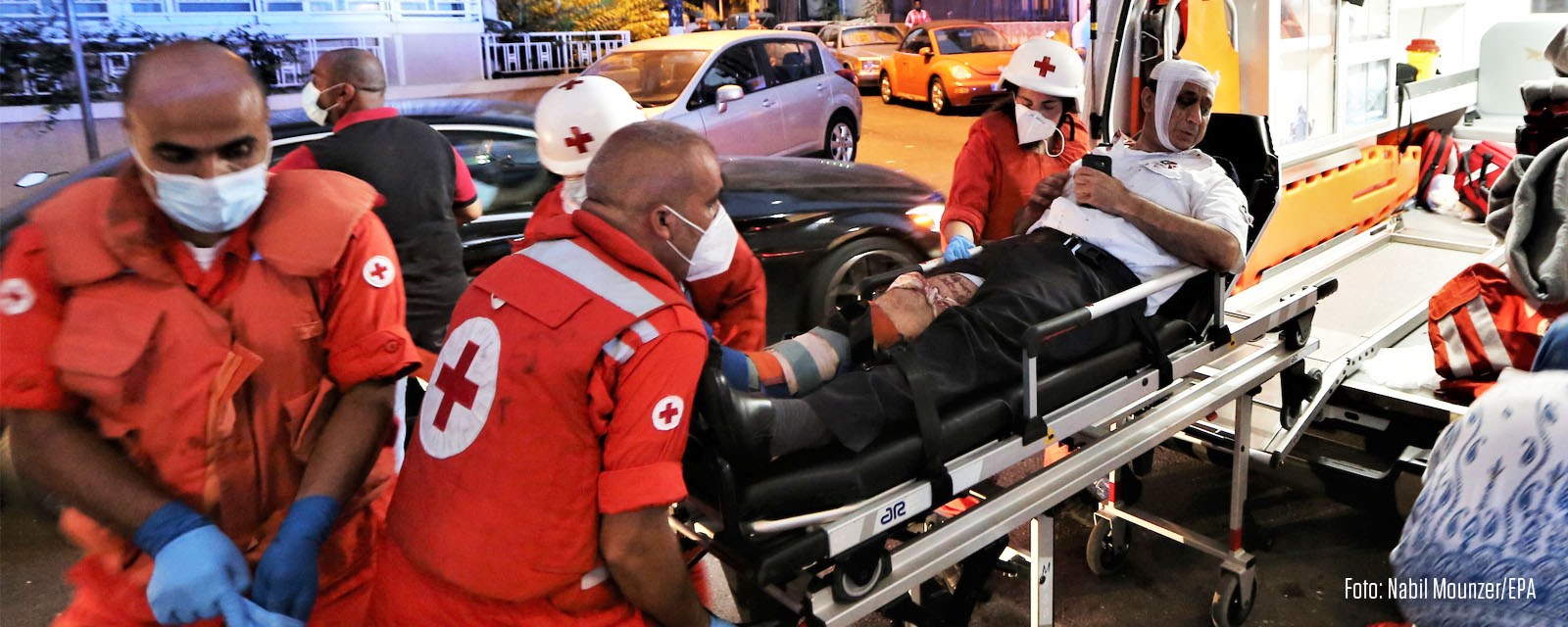 En skadet mann på båre blir løftet inn i ambulanse
