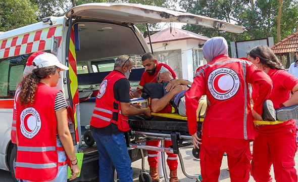 Syrisk Røde Halvmåne tar med skadet person på båre inn i ambulanse.
