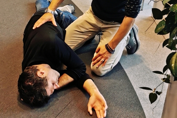 Mann ligger på gulvet i stabilt sideleie.