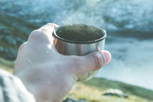 Kaffekopp det ryker av med natur i bakgrunnen