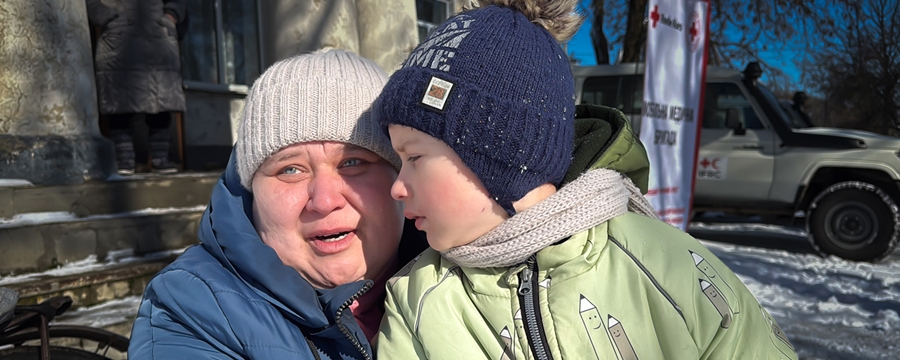 Nærbilde av en kvinne som holder rundt et barn, ute i vintervær.