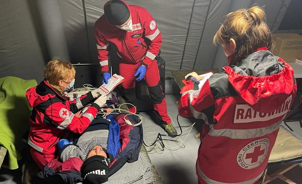 Helsearbeidere fra Røde Kors gir medisinsk hjelp til mann på båre