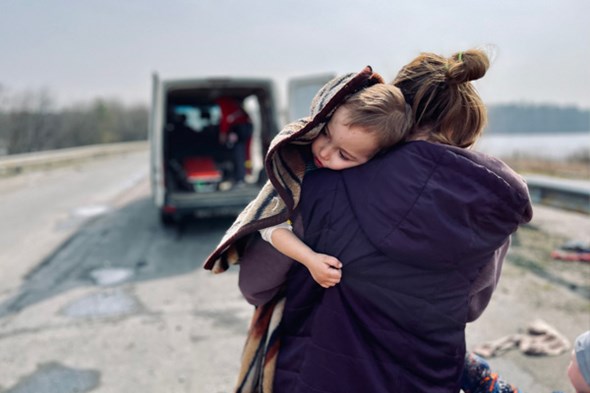 Mor som bærer sin datter i gatene i Ukraina.