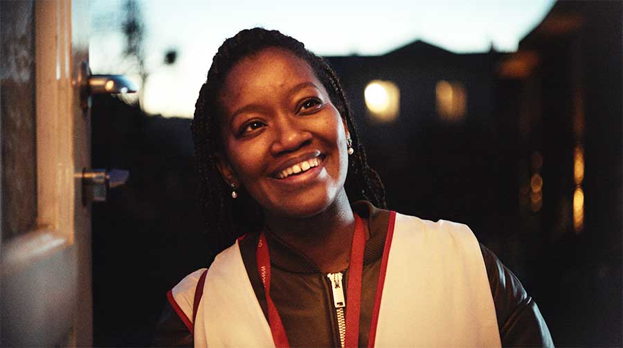 Jente står på dør og smiler