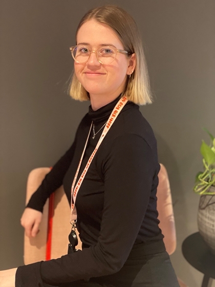 Kvinne sitter på stol og smiler