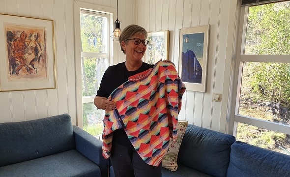 Kvinne holder en fargerik genser hun har strikket selv