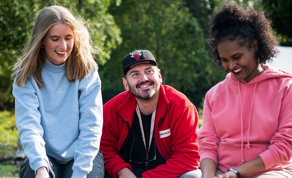 Tre personer rundt leirbål