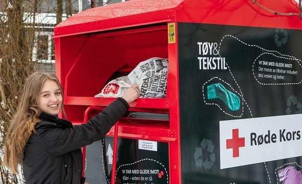 Jente gir tøy i innsamlingboksen til Røde Kors