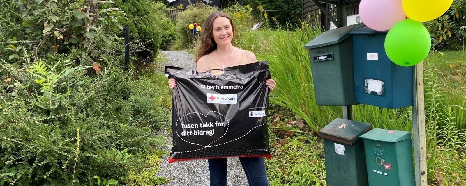 Kvinne holder pose med tøy til Røde Kors