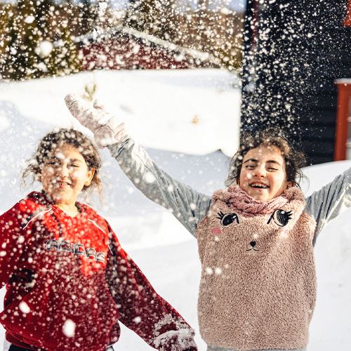 To jenter jubler og kaster snø