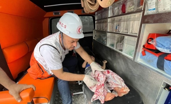 Frivillig gir førstehjelp til barn som er rammet av konflikten