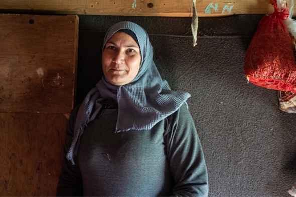 En kvinne kledd i grått med alvorlig uttrykk ser inn i kamera