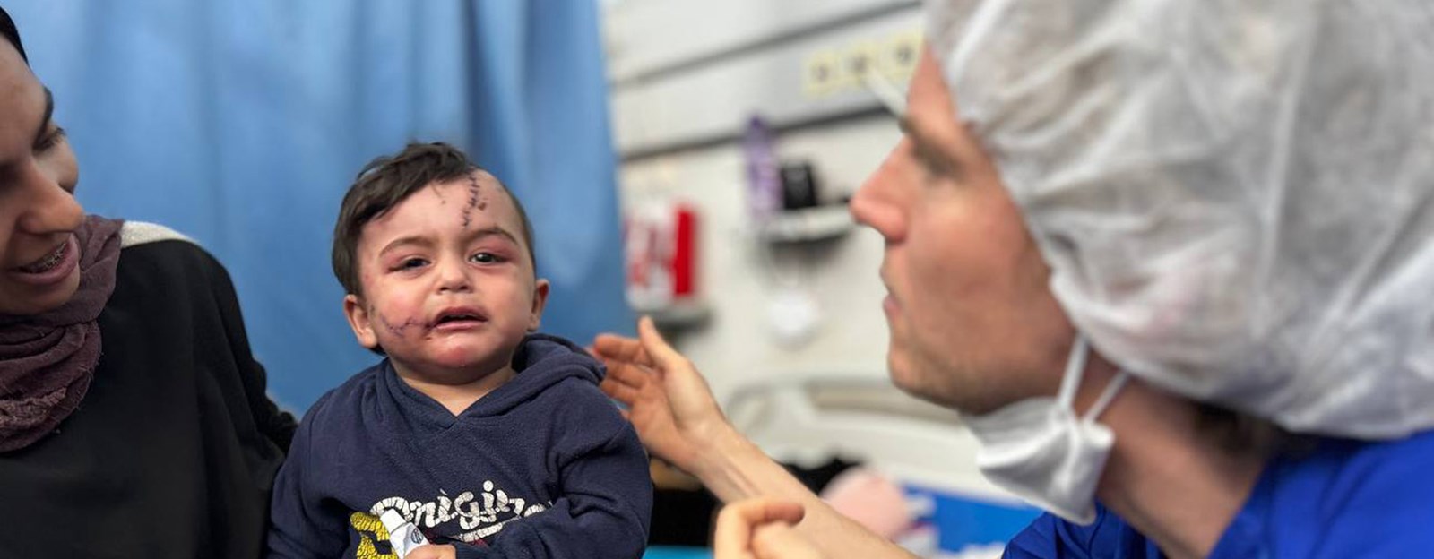 Et barn med sår i ansiktet blir sett på av en lege.