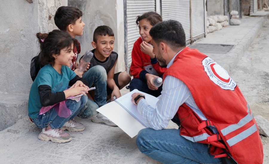 Mann sitter med ryggen til og snakker med smilende barn