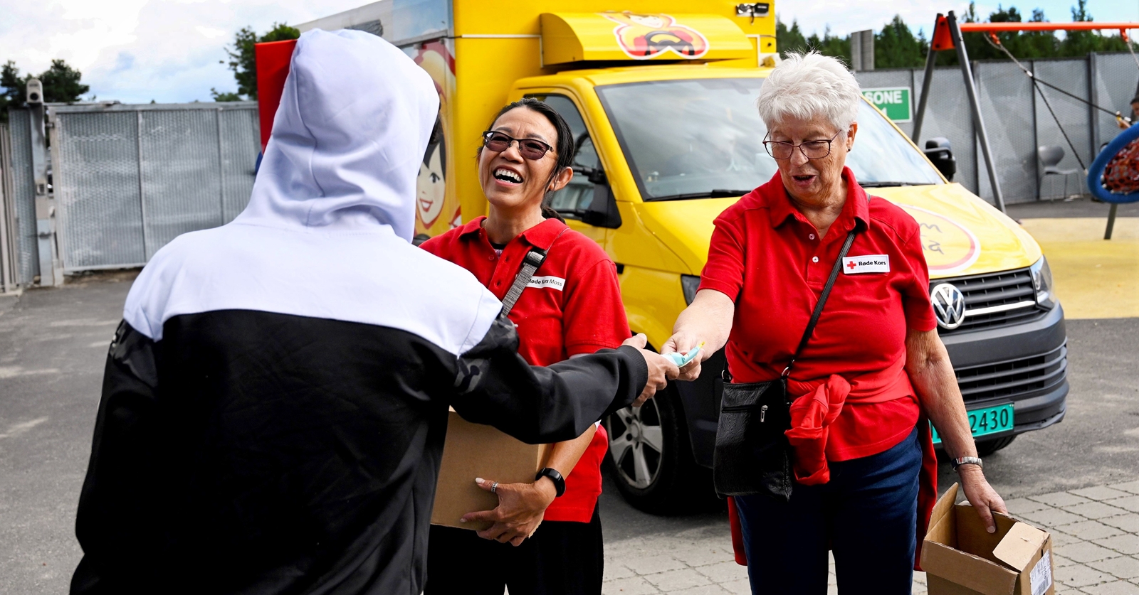 En person med ryggen til tar imot en is fra Røde Kors-frivillig.