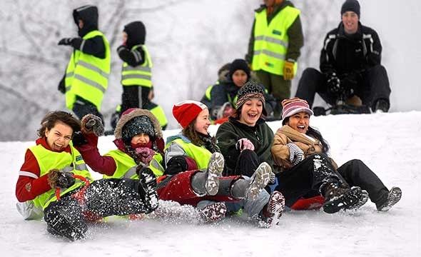 fem unge jenter aker i snødekket bakke