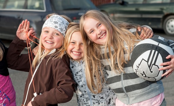 Fire jenter smiler mot kamera og holder rundt hverandre.