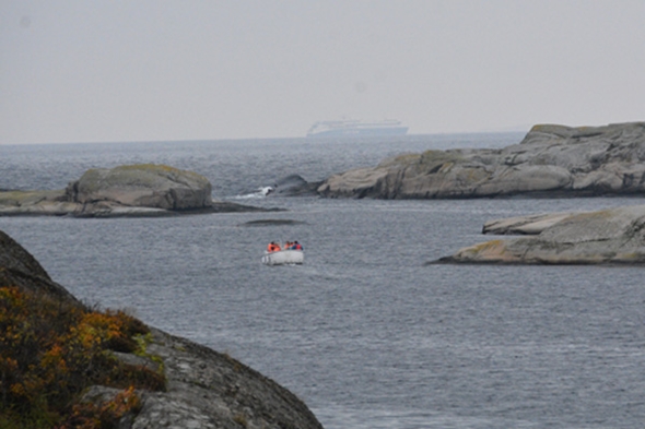 En båt langt ute på sjøen og svaberg