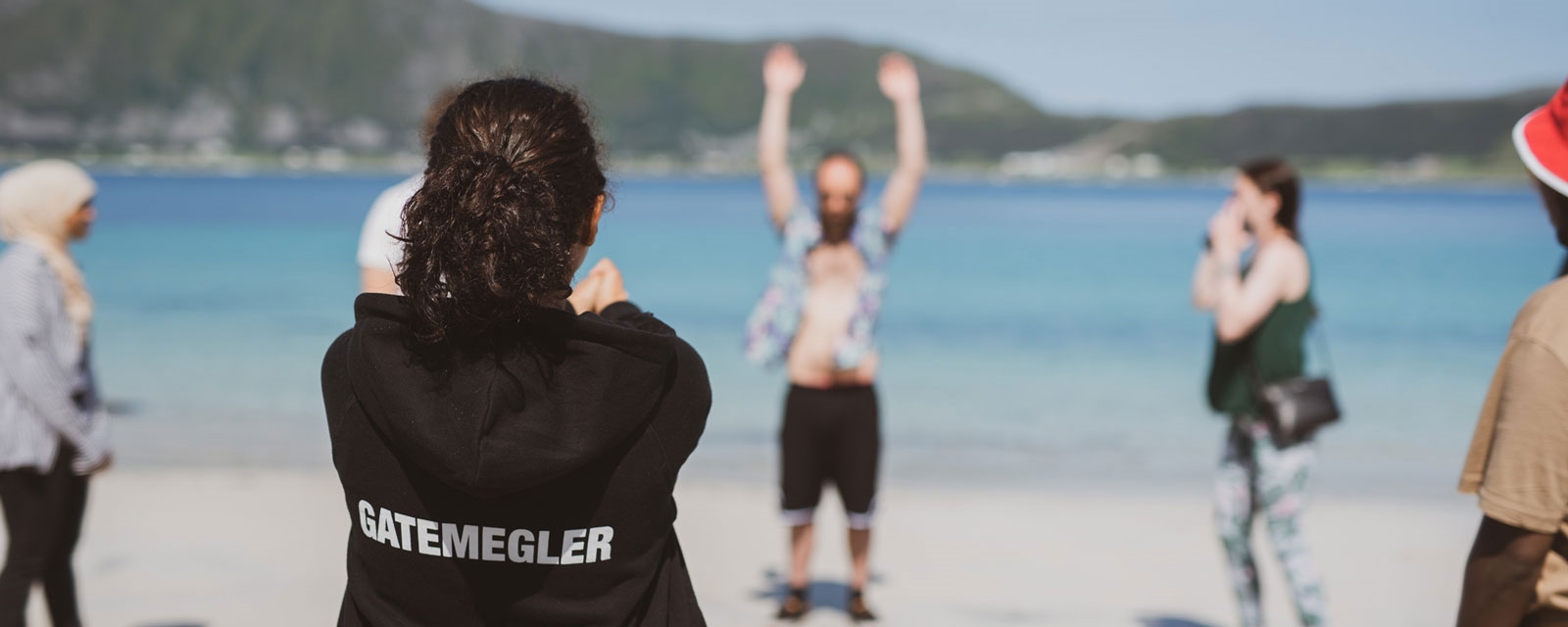 Gatemeglingsøvelser på stranda. Gatemegling står på ryggen av hettejakka