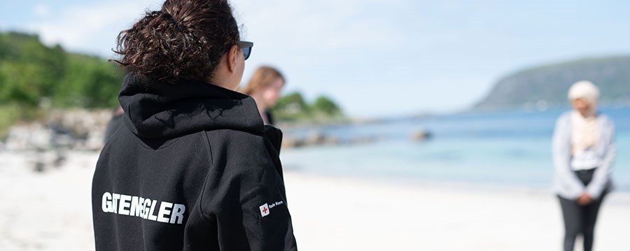 Kvinne med svart hoodie med gatemeglerlogo på ryggen . Strand sol, sommer