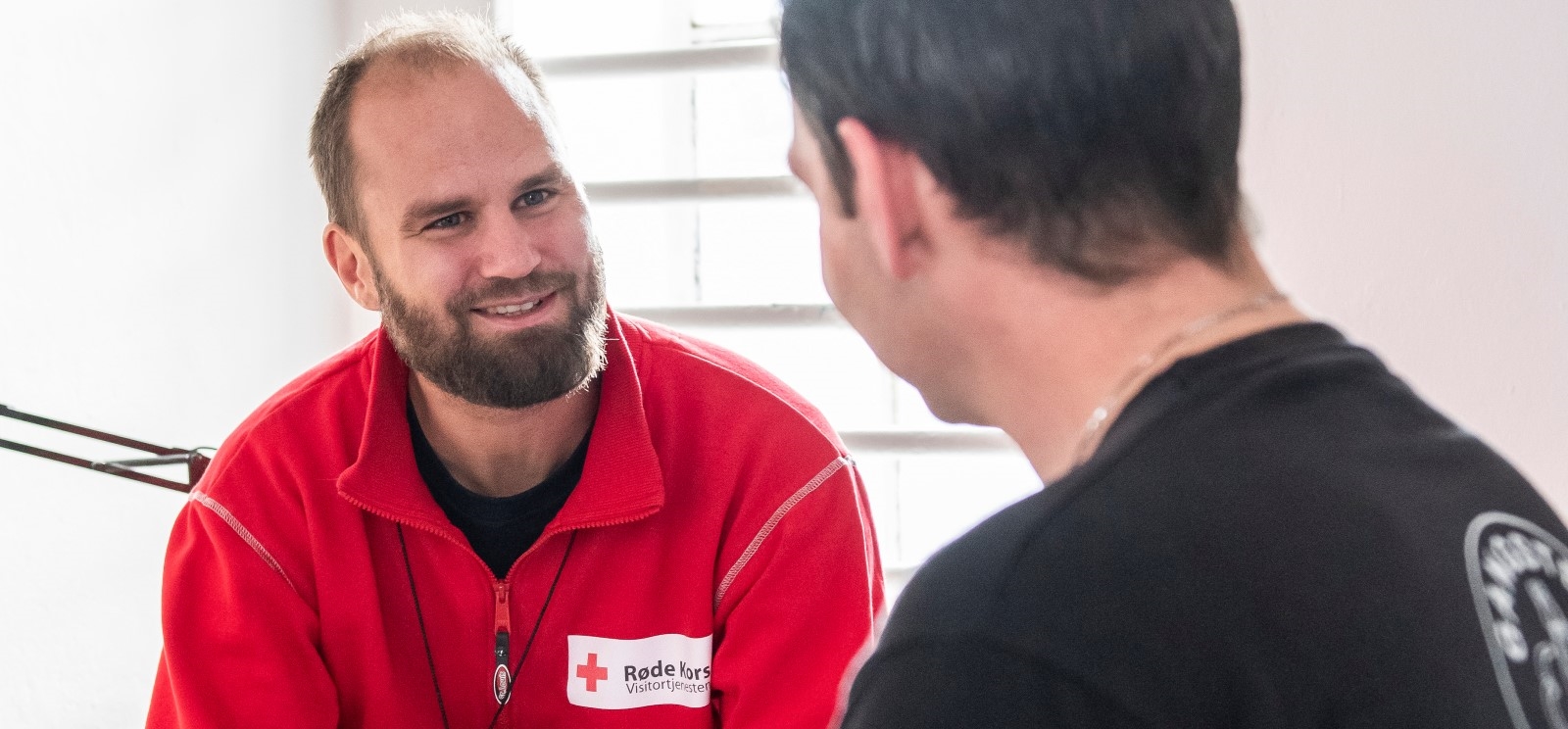 Manni rød fleece i samtale med mann