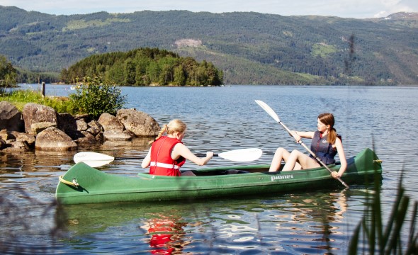 To jenter padler i en kano på et vann.