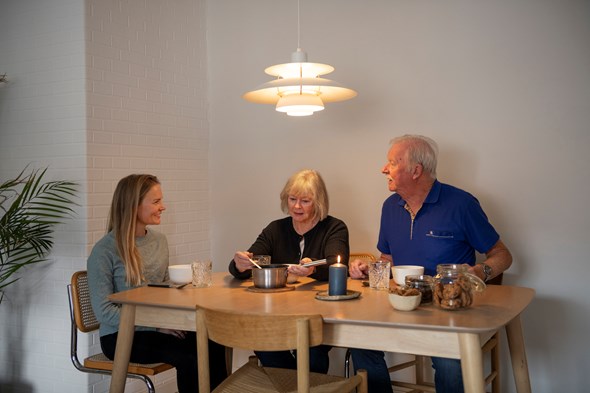 Tre personer rundt et middagsbord.