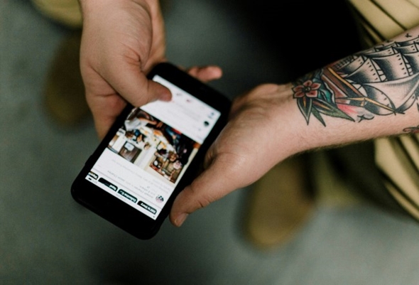 En mann sitter med en mobil i hånden og leser nyheter.