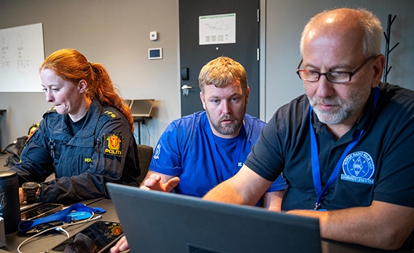 tre personer foran datamaskiner