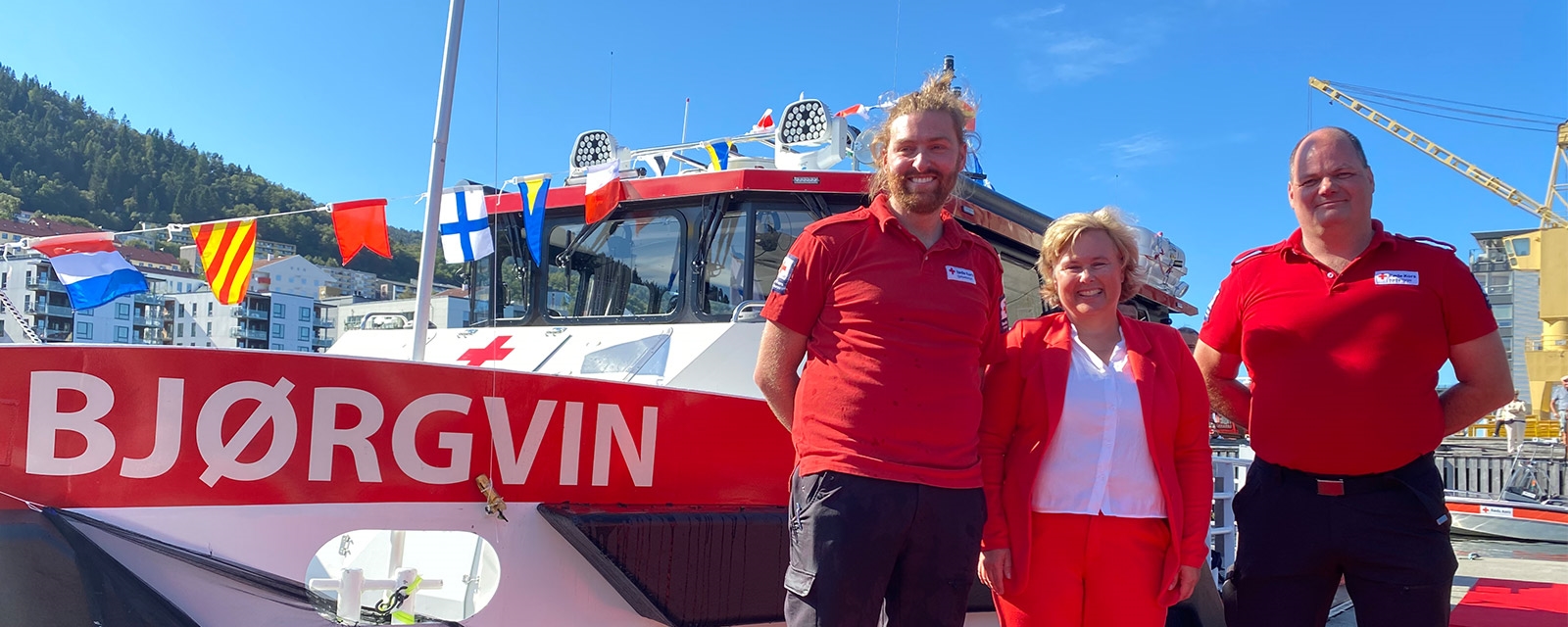 Tre mennesker foran Røde Kors-båten