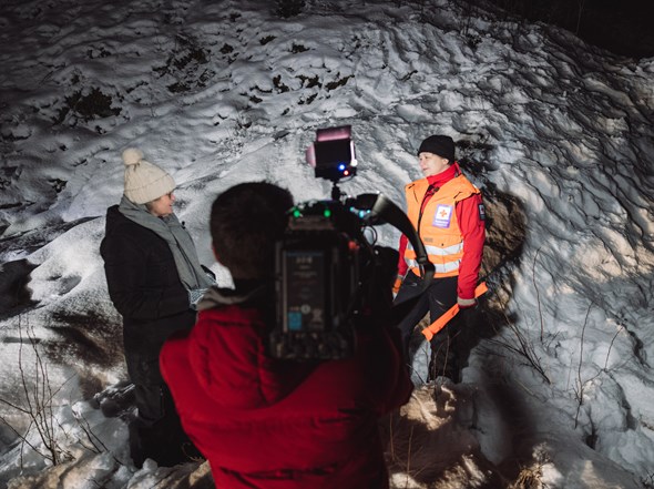 Røde Kors frivillig filmes og intervjues i mørket, foran snø.