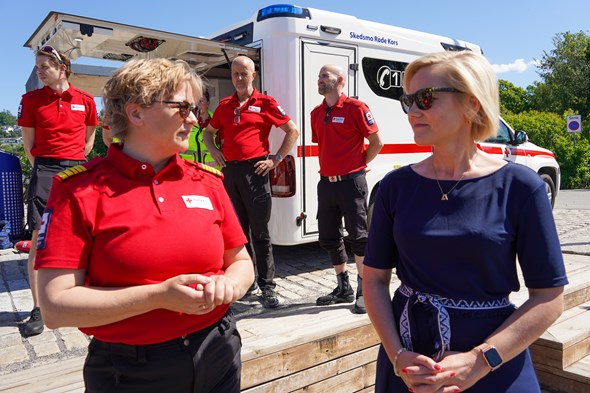 To kvinner - en Røde Kors-frivillig og en statsråd, prater sammen foran en beredsskapsambulanse.