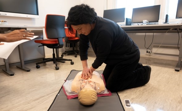 En kvinnelig innsatt øver på hjerte og lungeredning på en øvingsdukke.