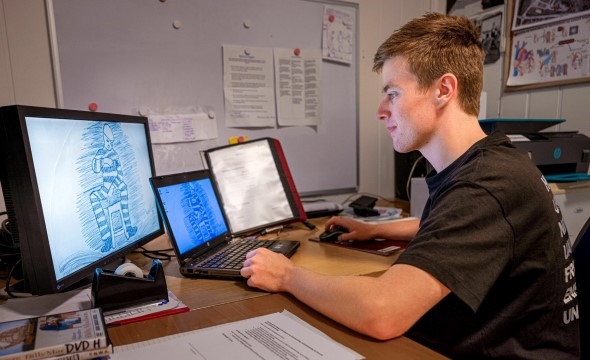 Truls sitter foran en PC-skjerm og ser på en tegning av en innsatt.